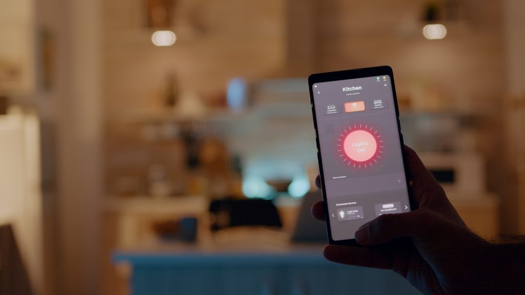 Man holding smartphone with lighting control application, turning on bulbs